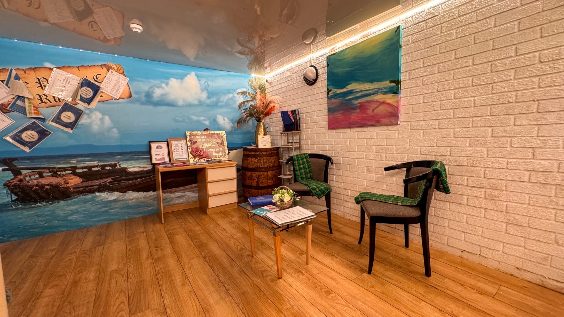 A consultation room at Mwanga with two armchairs, a desk and a painted coastal wall mural.
